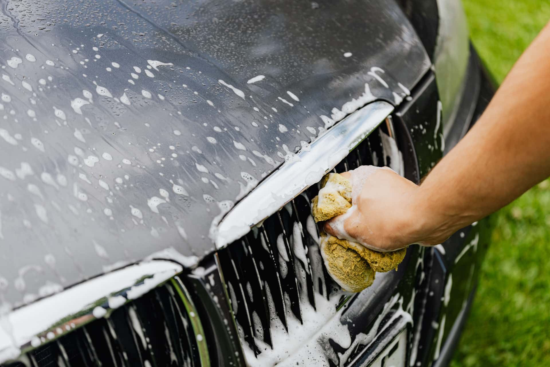 A car wash bucket of suds with a microfiber wash mitt