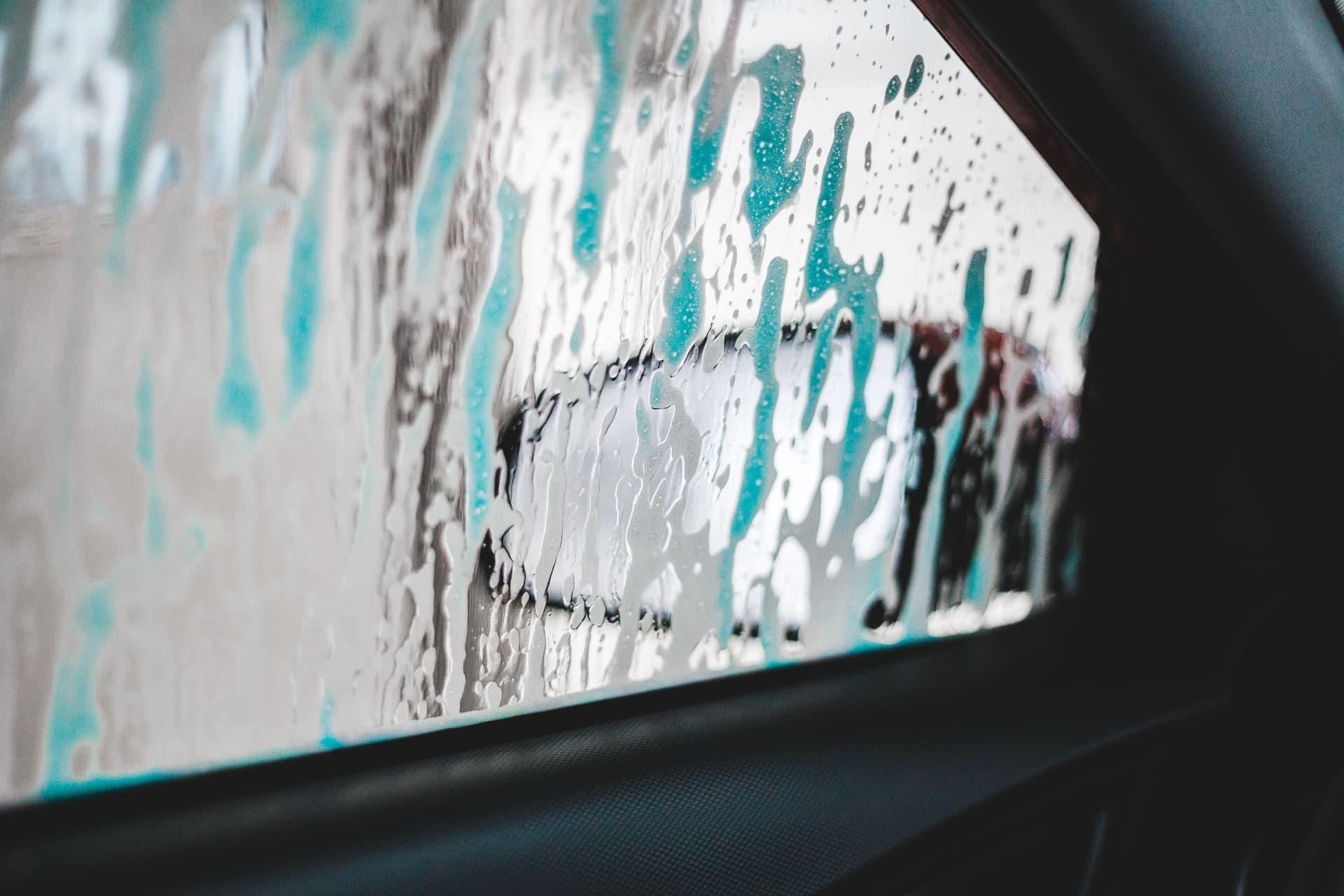 Soapy suds and water sheeting across a glossy car surface