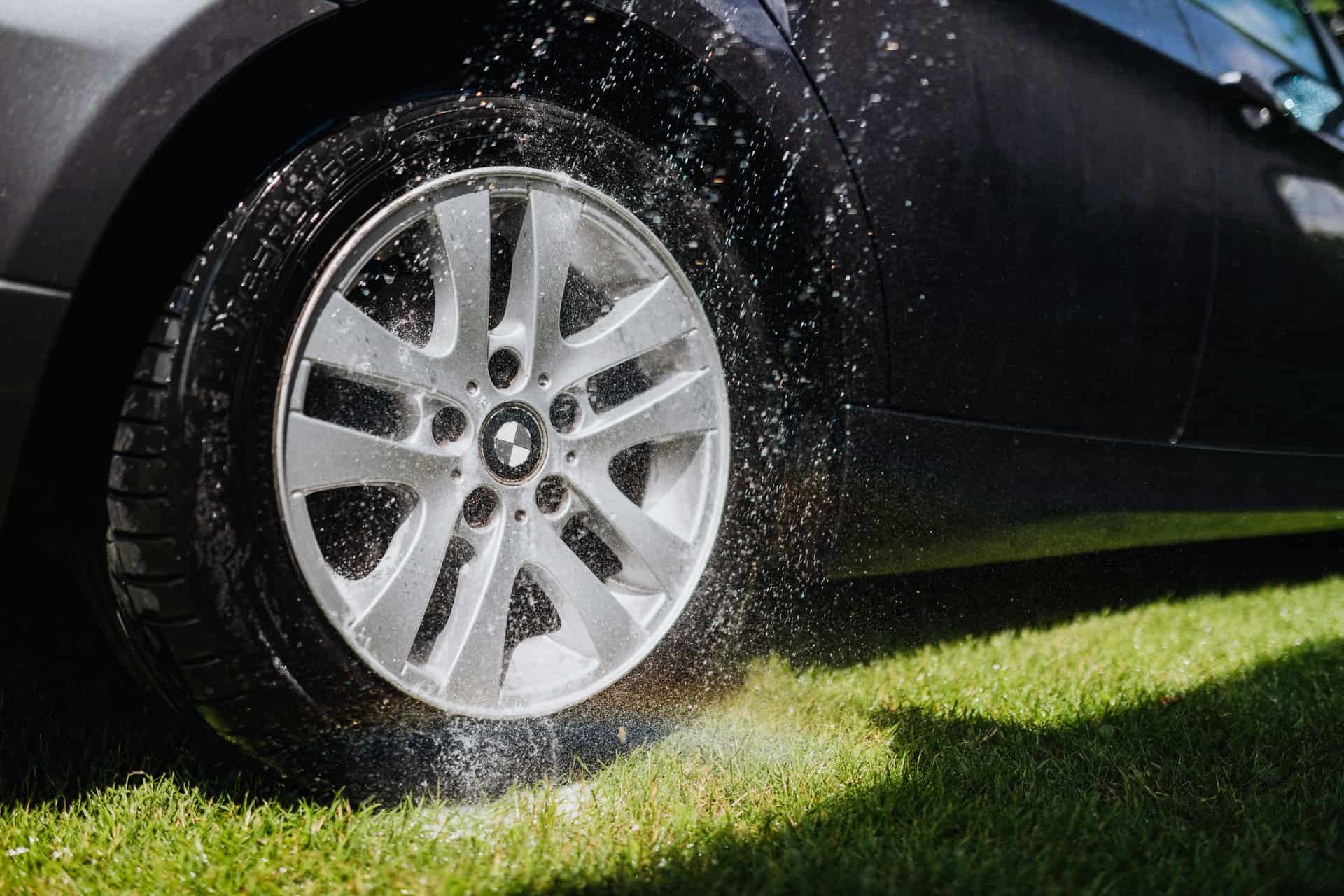 A car wheel and tire being rinsed clean with water
